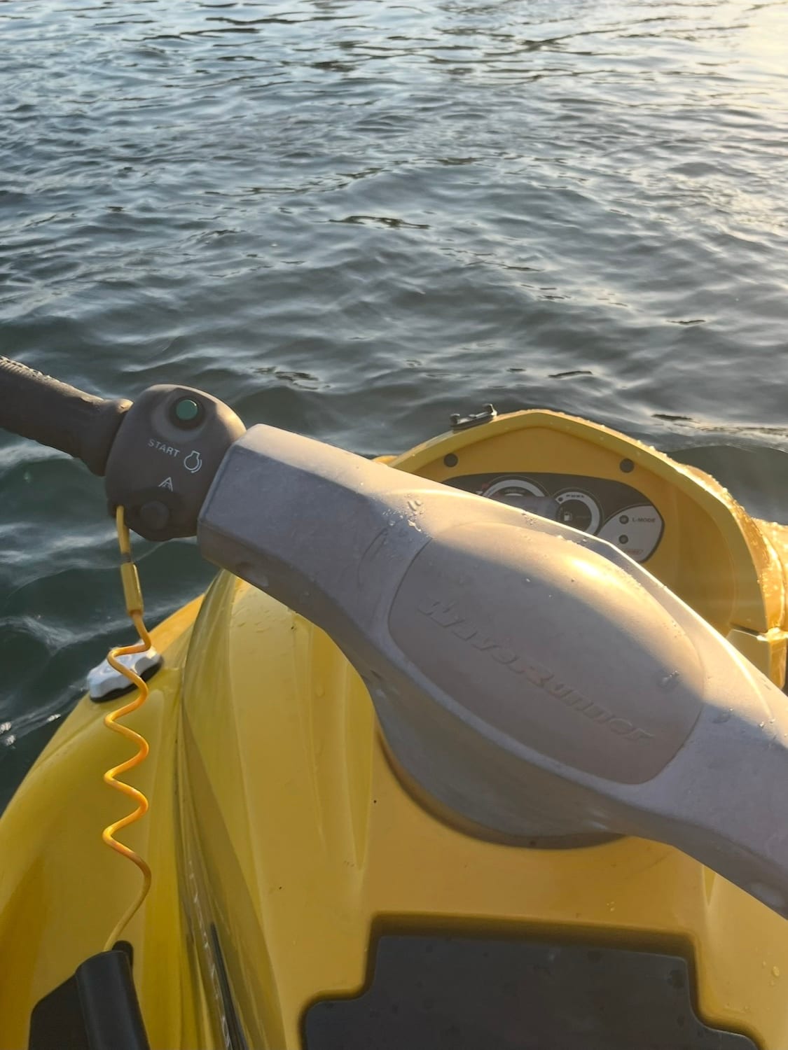 Close view over the handlebar of the yellow WaveRunner showing the start button and coiled safety lanyard